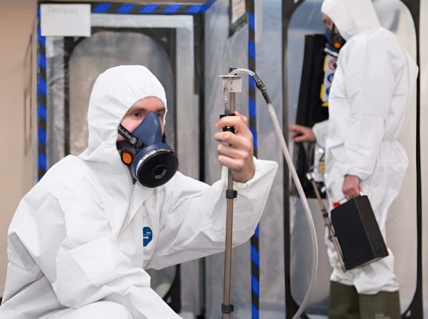 UKAS-accredited analyst carrying out independent asbestos air monitoring and clearance testing inside a sealed enclosure in Surrey